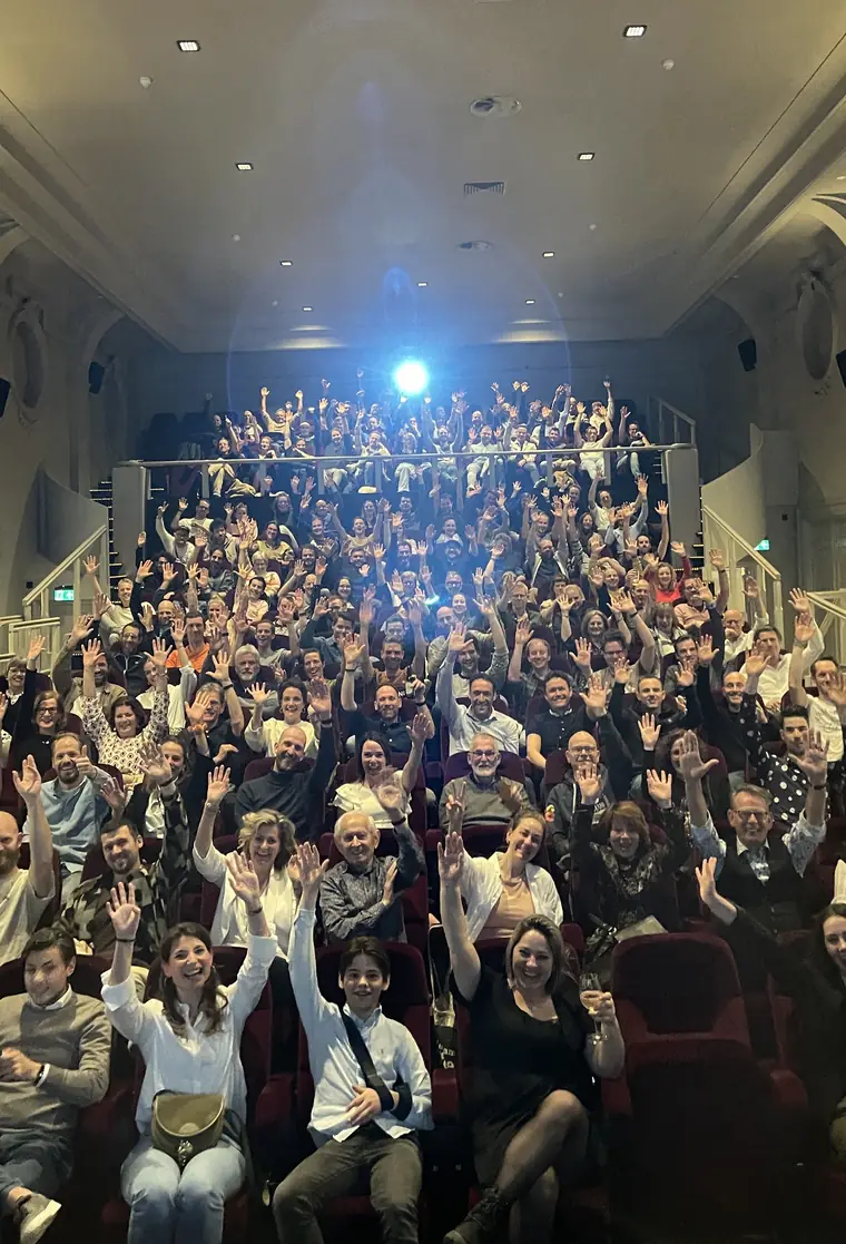 A packed cinema with the whole audience holding their hands in the air