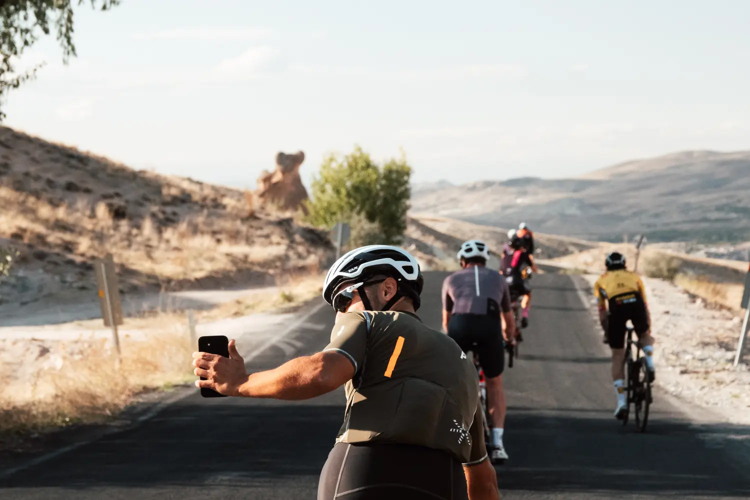 A rider filming the group ahead on a phone while riding