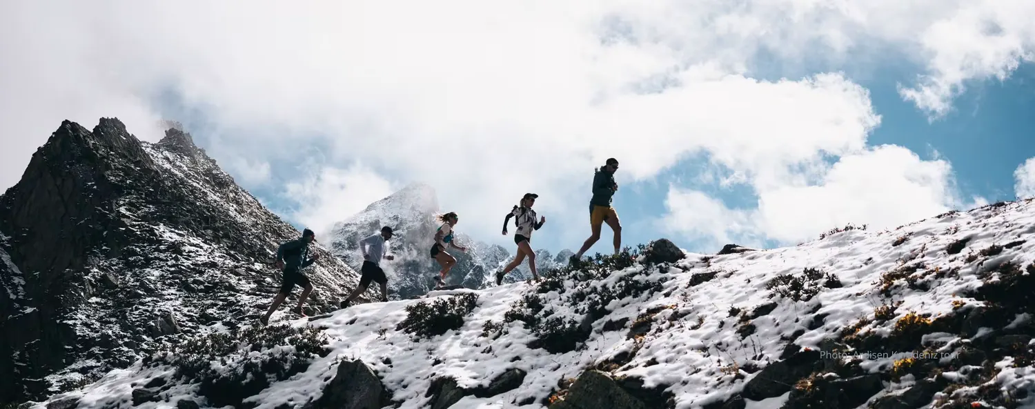 Trail runners on a snow-covered ridge in the Kaçkar Mountains above the clouds